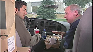 Two men eating in the car
