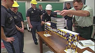A man in a military uniform shows a group of construction workers one of the leadreship lessons he learned at West Point