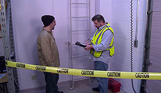A man in a bright yellow safety vest interviews a man in a windbreaker and a knit cap for an accident investigation case study