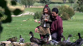 A father and his daughter feeding ducks