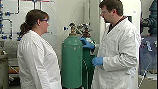 A man and a woman inspect a gas cylinder in the laboratory