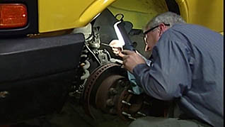 A worker inspects a car in the mechanic safety training video
