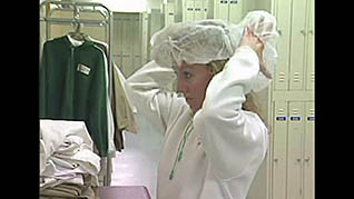 A woman putting on a hair net at a food manufacturing plant