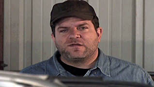 A man in a black baseball cap looking at the camera discussing Workplace Harassment, Discrimination and Respect