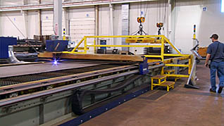 A man wearing a baseball cap oversseing an industrial apparatus to ensure that combustible dust is not spilling out into the workspace