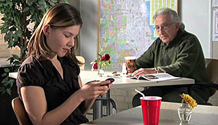 An elderly man sitting next to a young woman