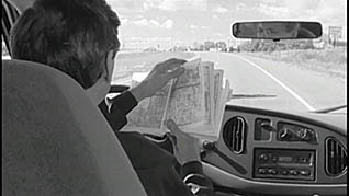 A man reads a book while driving a step van