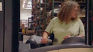 A woman driving a reach truck practices safe driving
