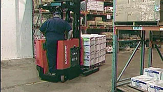 A man driving a reach truck carrying a palert of boxes