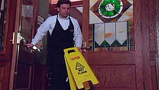 A man placing a wet floor sign