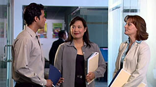 A man and two women stand together and discuss the day's work