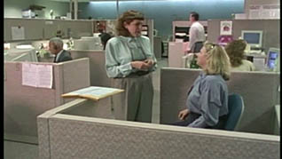Two women having a conversation in a cubicle