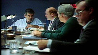 A meeting takes place in a boardroom in a screenshot from the Team Decision Making trianing video
