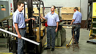 Two men standing in front of a fork lift