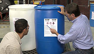 A man teaching an employee about the labels on barrel