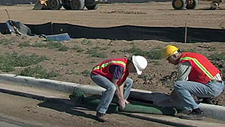 Two men covering a storm drain