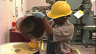 A man dumping hazardous waste into a barrel