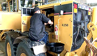 A man works on an industrial vehicle and properly disposes of the vehicle's liquids as part of SPCC