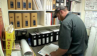 A man sits over a desk looking over SPCC documents