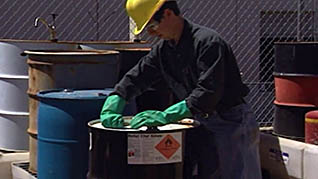 A man properly attending to a barrel with hazardous materials in it