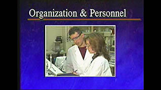A man and a woman in lab coats discuss good manufacturing practices
