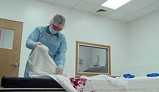 A medical professional cleaning blood stained sheets
