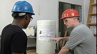 Two men read a GHS container label