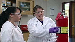 Two women discussing the importance of having a fire extinguisher in the lab