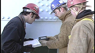 Three men in hard hats analyzing how to enter a confined space