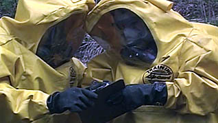 Two workers in hazmat suits working with toxic substances