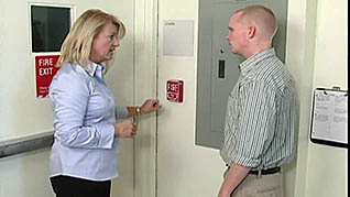 A women showing an employee where the fire alarm is