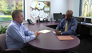 Two men talking at a desk