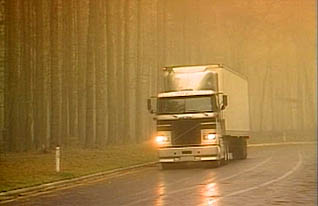A truck drives down a foggy highway slick with rain, demonstrating the best way to judge ditance and speed in a heavy truck with limited visibility.