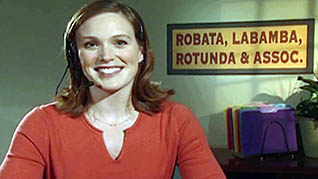 A smiling woman sitting at a desk in the communication skills training video