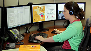 A woman working with three screens