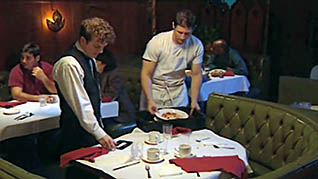 A waiter and a bus boy cleaning a table