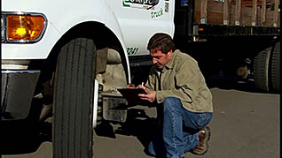 A driver checks the wheel during his pre-trip inspection