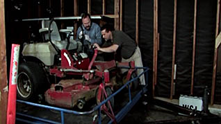 Two men fixing a lawn mower